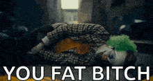 the joker is laying on the ground with the words `` you fat bitch '' written on the bottom .
