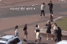 a group of people are standing in a parking lot taking pictures .