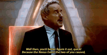 a man in a suit and tie is sitting in a chair and talking .