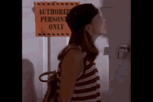 a woman is standing in front of a sign that says authorize person only .