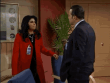 a man in a suit and a woman in a red coat talking
