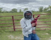 a man wearing a mask is holding a red gun .