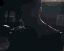 a man in a black shirt is playing drums in a dark room with a drum set in the background .