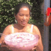 a woman is holding a large bowl of pink punch