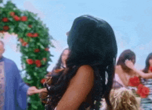 a woman with long hair is standing in front of a flower arch
