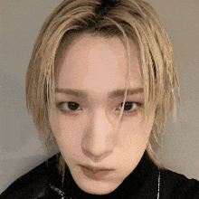 a close up of a person 's face with blonde hair and a black shirt