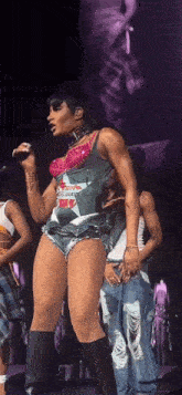 a woman in shorts is singing into a microphone on stage .