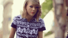 taylor swift is wearing a floral shirt and red lipstick while walking down a street .