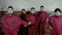 a group of men wearing pink and black plaid jackets are dancing together