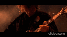 a close up of a person playing a guitar with the website clideo.com visible