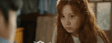 a woman with long red hair is looking at a man while holding a spoon .
