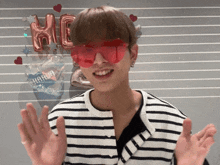 a young man wearing red sunglasses and a striped shirt stands in front of a sign that says hig