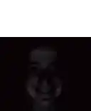a close up of a person 's face in the dark with a smiling face .