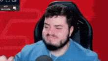 a man with a beard is sitting in a chair with his eyes closed and a microphone in his hand .