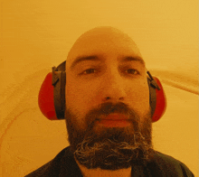 a bald man with a beard wearing red ear defenders