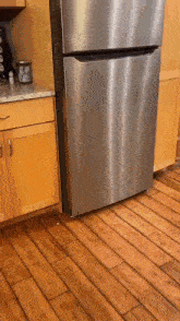 a stainless steel refrigerator is in a kitchen with wooden floors