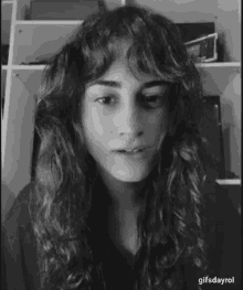 a black and white photo of a woman with long curly hair making a face .