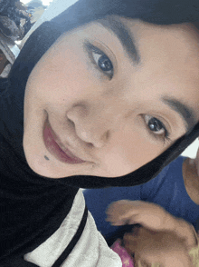 a woman wearing a black hijab looks at the camera