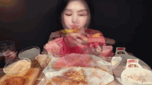 a woman is sitting at a table eating a slice of pizza with a box of ketchup on it