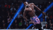 a wrestler is jumping in the air while another wrestler watches