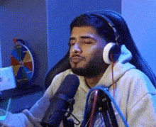 a man wearing headphones is sitting in front of a microphone in a room .