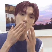 a young man with red hair is covering his mouth with his hands
