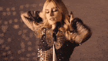 a woman in a sequined top is singing into a microphone .