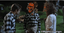 a man in a plaid shirt is talking to a woman and another man
