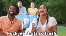 a man and a woman are holding bottles of laundry detergent and a group of people are behind them .