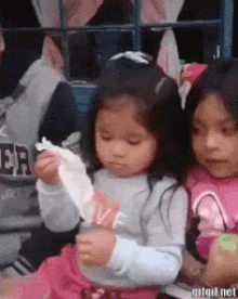 two little girls are sitting next to each other and one of them is wearing a shirt that says love