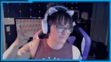 a woman wearing cat ears and glasses is giving a thumbs up while sitting in front of a computer .