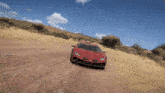 a red sports car driving down a dirt road