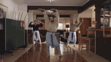 a group of men are dancing in a living room with their arms in the air
