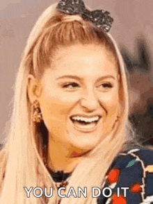a woman with a bow in her hair is laughing and smiling .