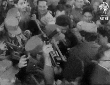 a black and white photo of a crowd with pathe written on the bottom right