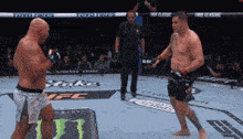 two men are fighting in a boxing ring with a monster energy sign on the floor