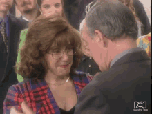a man and a woman are hugging in front of a nuestra tele screen