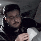 a man with a beard is sitting in the back seat of a car with his eyes closed .