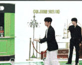 a man in a black suit is standing in front of a green counter with a sign that says ' k ' on it
