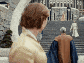 a group of people are walking down stairs in front of a stone building