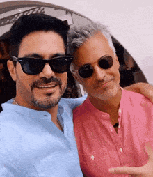 two men wearing sunglasses are posing for a photo