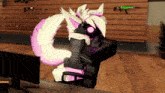 a pink and white furry character is sitting in front of a computer monitor