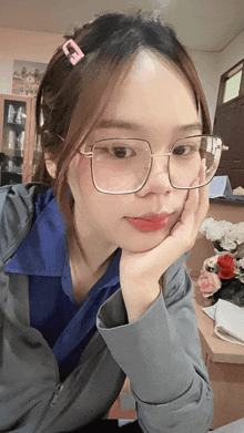 a girl wearing glasses and a hair clip has her hand on her face