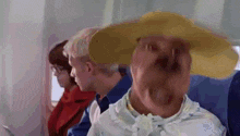 a woman wearing a hat is sitting on an airplane with other people .