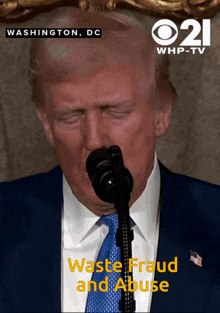 a man in a suit and tie speaking into a microphone with the words waste fraud and abuse above him
