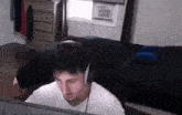 a man wearing headphones is sitting in a bedroom .