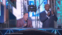 two men standing on a stage with microphones and the words americanninjawarrior on the bottom
