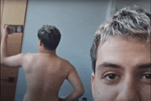 a shirtless man taking a picture of himself in the mirror