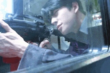 a man is holding a gun in front of a glass window