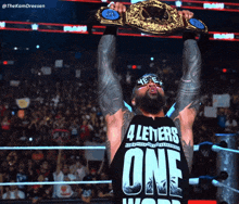 a wrestler wearing a shirt that says 4 letters one holds up his championship belt